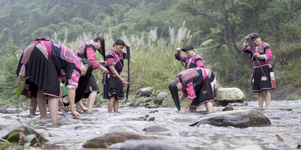 Frauen waschen ihre langen Haare im Fluß